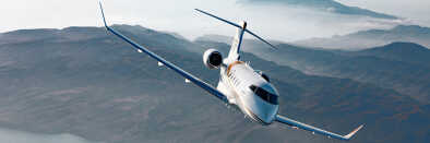 Bombardier Challenger 350 im Flug über nebelbedeckte Berglandschaft Bombardier Challenger 350 im Flug über nebelbedeckte Berglandschaft