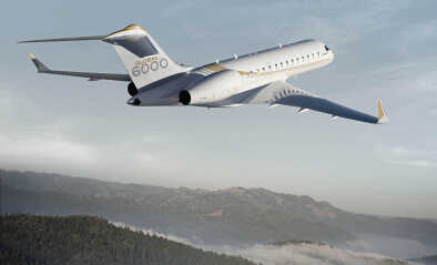Bombardier Global Express 6000 im Flug über eine teilweise mit Nebel bedeckte Berglandschaft