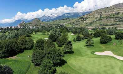 Vista aérea de un campo de golf cerca de Sion junto a la falda de una montaña Vista aérea de un campo de golf cerca de Sion junto a la falda de una montaña