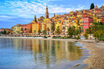 Playa de arena bajo el colorido casco antiguo de Menton en la Riviera Francesa, Francia Playa de arena bajo el colorido casco antiguo de Menton en la Riviera Francesa, Francia