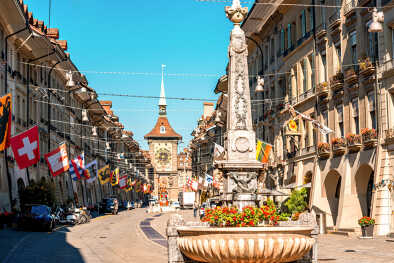 Vista de la calle Kramgasse con la fuente y la torre del reloj en el casco antiguo de la ciudad de Berna. Es una popular calle comercial y centro de la ciudad medieval de Berna, Suiza Vista de la calle Kramgasse con la fuente y la torre del reloj en el casco antiguo de la ciudad de Berna. Es una popular calle comercial y centro de la ciudad medieval de Berna, Suiza