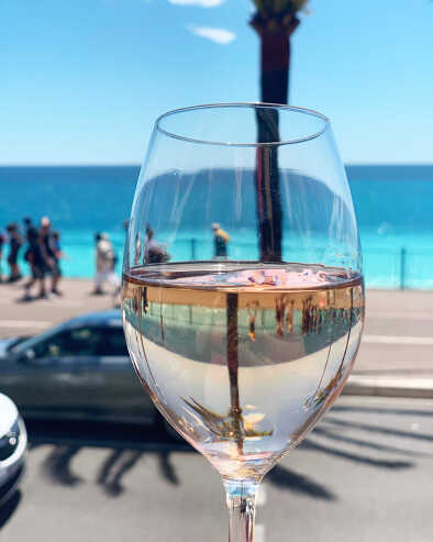 Copa de vino blanco en Niza, francia, frente al paseo marítimo, durante una cata Copa de vino blanco en Niza, francia, frente al paseo marítimo, durante una cata