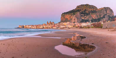 Schöner Panoramablick auf den Strand, die Kathedrale von Cefalu und die Altstadt der Küstenstadt Cefalu bei rosa Sonnenuntergang, Sizilien, Italien