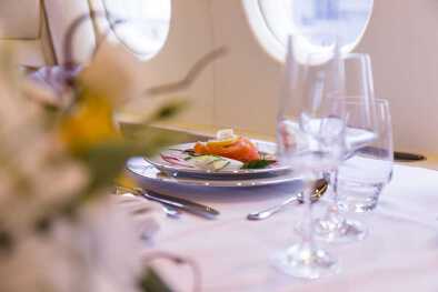 Una elegante mesa de comedor con comida gourmet en un plato en una cabina de jet privado