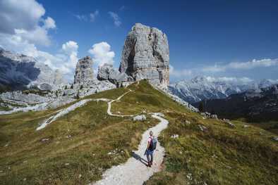 Escursionista con zaino in spalla esplora le Cinque Torri nelle Dolomiti, Italia
