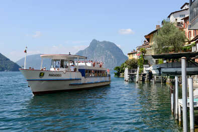 Gente disfrutando de la vista durante un crucero turístico por el lago Lugano en Gandria, Suiza