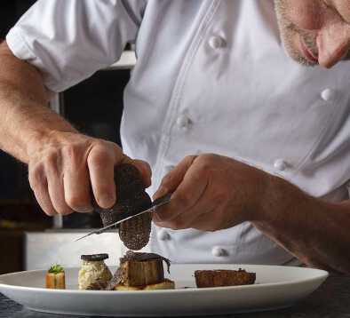 Lo chef guarnisce un piatto con scaglie di tartufo