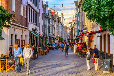 Gente paseando por una calle céntrica en el centro histórico de Dusseldorf, Alemania, frente a una terraza café