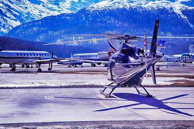 Ein Hubschrauber und Privatflugzeuge in einem verschneiten Skigebiet