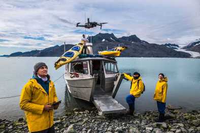 Investigadores científicos con un bote y un dron en un lago ártico 