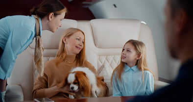 Die Flugbegleitung nimmt auf dem Flug eine Bestellung auf von einer Mutter mit Ihrer Tochter und Hund an Bord des Privatjets Die Flugbegleitung nimmt auf dem Flug eine Bestellung auf von einer Mutter mit Ihrer Tochter und Hund an Bord des Privatjets
