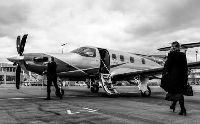 Femme d'affaires marchant vers le Pilatus PC-12, sur la piste de décollage Femme d'affaires marchant vers le Pilatus PC-12, sur la piste de décollage