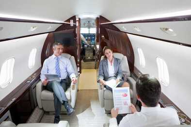 Geschäftsleute halten eine private Geschäftsbesprechung in einer Privatjet-Kabine ab Geschäftsleute halten eine private Geschäftsbesprechung in einer Privatjet-Kabine ab