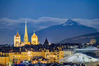 Vista nocturna de Ginebra con los Alpes y la Catedral de Saint Pierre