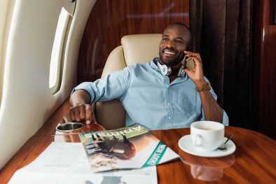Un hombre se relaja y sonríe escuchando los auriculares en un avión privado Un hombre se relaja y sonríe escuchando los auriculares en un avión privado