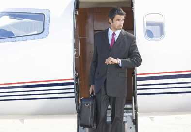 Un elegante hombre de negocios con traje desciende los escalones de un jet privado Entorno Un elegante hombre de negocios con traje desciende los escalones de un jet privado Entorno