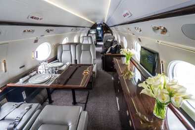 El interior de un espacioso jet privado , con flores y mesas de comedor El interior de un espacioso jet privado , con flores y mesas de comedor
