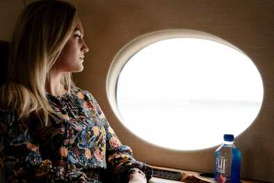 Junge Frau in einem Privatjet, die die Aussicht nach draußen genießt Junge Frau in einem Privatjet, die die Aussicht nach draußen genießt