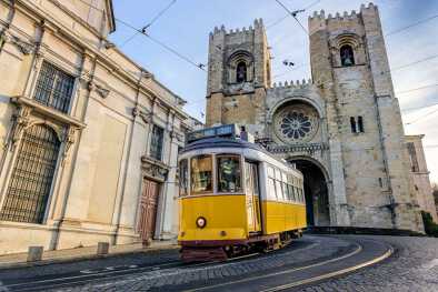 Un famoso tranvía amarillo 28 que pasa frente a la catedral de Santa María en Lisboa, Portugal.

