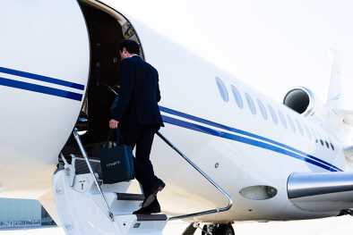 Geschäftsmann, der mit einer Tasche der Marke LunaJets in einen Privatjet einsteigt Geschäftsmann, der mit einer Tasche der Marke LunaJets in einen Privatjet einsteigt