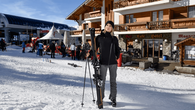 Esquiadora en la calle nevada frente a la recepción del Hotel Magrappé a pié de una pista de esquí en los montes nevados en un invierno de Sion