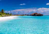 Вид на пляж на Мальдивах с отелем на сваях над бирюзовой водой