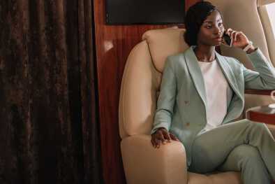 Una mujer africana exitosa -Empresaria estadounidense hablando por teléfono en un jet Una mujer africana exitosa -Empresaria estadounidense hablando por teléfono en un jet