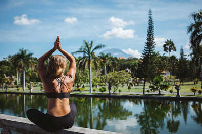 una mujer practica yoga en un lugar exótico junto a una piscina