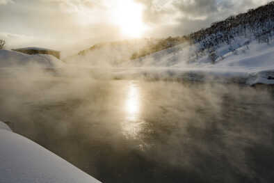 Il sole brilla attraverso il vapore delle sorgenti termali vulcaniche naturali di Hokkaido, Giappone
