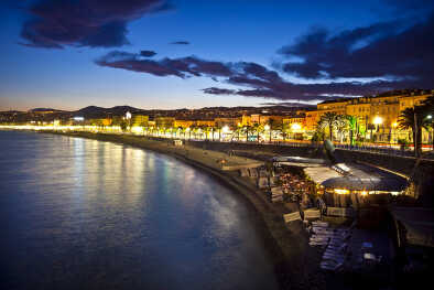 La playa y el paseo marítimo de Niza por la noche, Francia. Iluminación nocturna frente al mar con el monte de fondo La playa y el paseo marítimo de Niza por la noche, Francia. Iluminación nocturna frente al mar con el monte de fondo