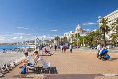 Menschen genießen sonniges Wetter und den Blick auf das Mittelmeer an der englischen Promenade (Promenade des Anglais), einem großartigen Ort zum Wandern, Joggen, Radfahren oder einfach zum Entspannen