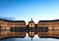 La place de la Bourse di Bordeaux con il tram che si riflette nel Miroir d'eau al tramonto