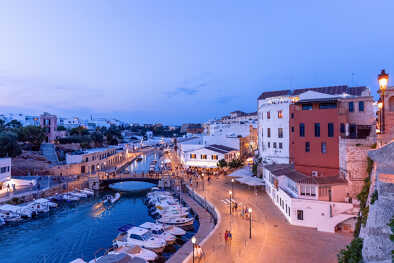 Vista del antiguo puerto de la ciudad de Ciutadella con barcos y restaurantes (hermosa luz nocturna)