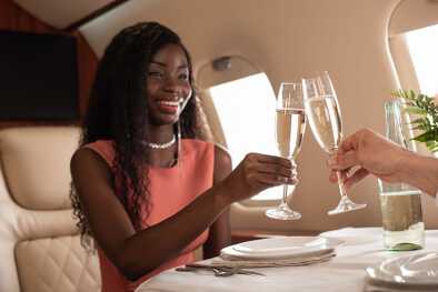 Una sorridente dirigente donna a bordo di un jet privato, mentre brinda con lo champagne Una sorridente dirigente donna a bordo di un jet privato, mentre brinda con lo champagne