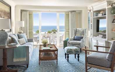 Zimmer mit Möbeln und TV, mehreren Sesseln und Blick auf die Bucht von Shutters on The Beach Hotel.