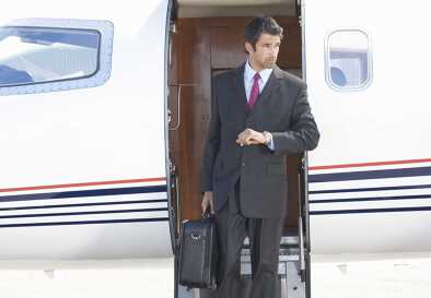 Ein smarter Geschäftsmann im Anzug steigt die Stufen eines Privatjets hinab Ein smarter Geschäftsmann im Anzug steigt die Stufen eines Privatjets hinab