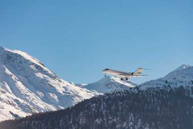 Un jet privé volant à faible distance au-dessus de montagnes enneigées