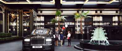 Un chófer recibe a una familia en el hotel The Savoy junto a la limusina Un chófer recibe a una familia en el hotel The Savoy junto a la limusina