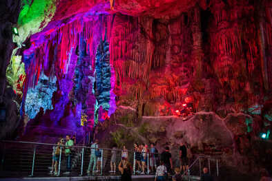 Los turistas exploran la antigua cueva de San Miguel, que ha sido iluminada con luces LED de colores, situada en la Reserva Natural del Peñón Superior de Gibraltar.
