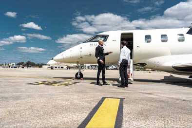 The captain and a passenger chatting in front of a private jet The captain and a passenger chatting in front of a private jet