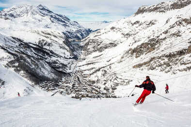 Esquiadores en la pista con el pueblo de Val d'isere al fondo. Val d'isere, Francia