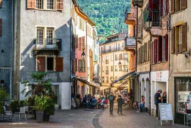Gente en una calle peatonal en un día soleado de verano con una luz espectacular en el casco antiguo de Sion, Suiza Gente en una calle peatonal en un día soleado de verano con una luz espectacular en el casco antiguo de Sion, Suiza