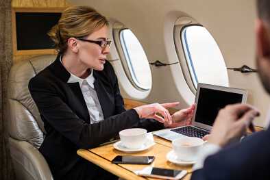 Una donna d'affari elegantemente vestita al computer in un jet privato