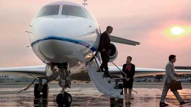 Two business man happily exiting a private jet in the sunset